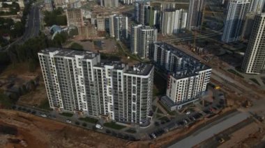 Modern bir şehir bloğunun inşaatı. Çok katlı binalar ve şehir altyapısının unsurları. İnşaat işleri ve binaların inşaatı devam ediyor. Gün batımında hava fotoğrafçılığı.