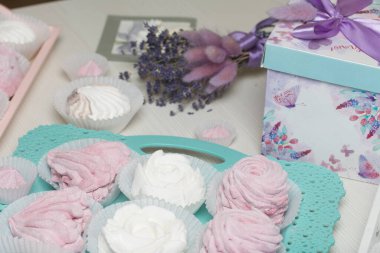 Çeşitli renk ve tatlardan ev yapımı marşmelovlar. Tepside yatıyor. Sırada bir kutu hediye ve bir demet lavanta var..