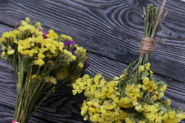 İki buket statik. Biri sarı, diğeri çok renklidir. Çam ağacının arka planında.