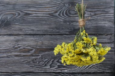 Sarı renkli buket. Çam ağacının arka planında bir iplikle askıya alınmış.