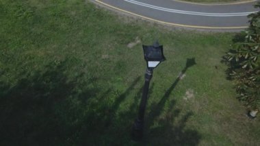 Şehir parkında uçuş. Aşağıda virajlı bisiklet yolu görülebilir. Güçlü bir rüzgar ağaçları sallıyor. Hava fotoğrafçılığı.