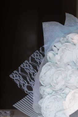 Marshmallow buketleri el işi paketlemede. Marşmelov gülleri ve lalelerden oluşuyor. Buketler masa yüzeyinde yatıyor. Yakın çekim..