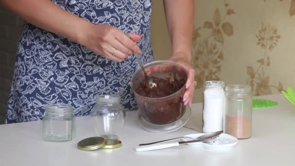 Uma mulher mistura manteiga de noz em uma tigela de liquidificador. Muda-o para o frasco. Urbech de noz. Os ingredientes estão na mesa lado a lado. — Vídeo de Stock