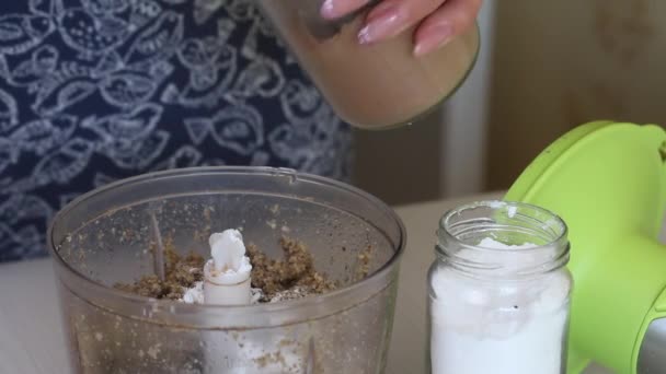 Eine Frau gibt gehackten Nüssen in einer Mixer-Schüssel Kakao hinzu. Nussbutter kochen. Walnussbaum. Die Zutaten liegen nebeneinander auf dem Tisch. Nahaufnahme. — Stockvideo