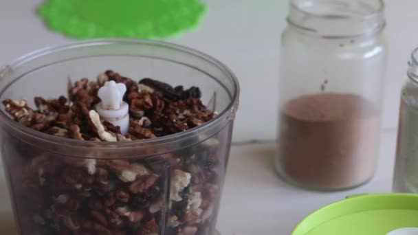 Bak notenboter. Walnoot egel. Noten in een blender kom, poedersuiker en cacao liggen naast elkaar op tafel. — Stockvideo