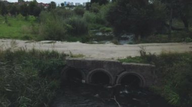 Beton kanalizasyonların üzerinden uçuyor. Su akıntıları beton borulardan akar. Parktaki kirli su kütlesi. Hava fotoğrafçılığı.