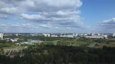 Şehir manzarası. Yakınlarda bir park alanı var. Beyaz bulutlu mavi gökyüzü. Hava fotoğrafçılığı.