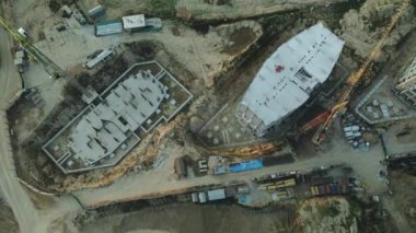 Modern bir şehir bloğunun inşaat alanı. Yüksek binalar yapım aşamasında. İnşaat kulesi vinçleri. Gün batımında hava fotoğrafçılığı.