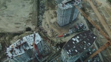 Modern bir şehir bloğunun inşaat alanı. Yüksek binalar yapım aşamasında. İnşaat kulesi vinçleri. Gün batımında hava fotoğrafçılığı.