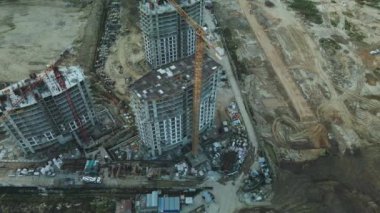 Modern bir şehir bloğunun inşaat alanı. Yüksek binalar yapım aşamasında. İnşaat kulesi vinçleri. Gün batımında hava fotoğrafçılığı.