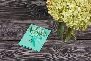 El yapımı kartpostal. Yakınlarda kartpostal yapmak için malzemeler var. Siyah çam tahtalarında.