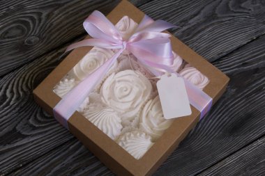 Hediye kutusunda ev yapımı marşmelov. Fiyonka bağlanmış bir kurdeleyle bağlanmış. Siyah çam tahtalarında.