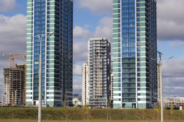 Modern çok katlı binaların yapımı. Yeni bir şehir bloğu inşaatı. İnşaat ve kule vinçleri altında binalar.