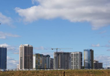 Modern çok katlı binaların yapımı. Yeni bir şehir bloğu inşaatı. İnşaat ve kule vinçleri altında binalar.