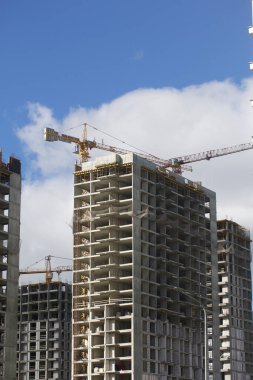 Modern çok katlı binaların yapımı. Yeni bir şehir bloğu inşaatı. İnşaat ve kule vinçleri altında binalar.