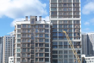 Modern çok katlı binaların yapımı. Yeni bir şehir bloğu inşaatı. İnşaat ve kule vinçleri altında binalar.