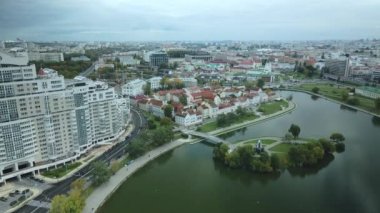 Bulutlu havada şehrin üzerinde uçmak. Modern binalar ve eski kasaba görülebilir. Nehir akıyor. Hava fotoğrafçılığı.