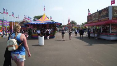 Falcon Heights, Minnesota 'da. Minnesota eyalet fuarı. İnsanlar yolun ortasındaki caddelerden birinde yürüyor. Satıcıları ve yol boyunca at binenleri kontrol ediyorlar..