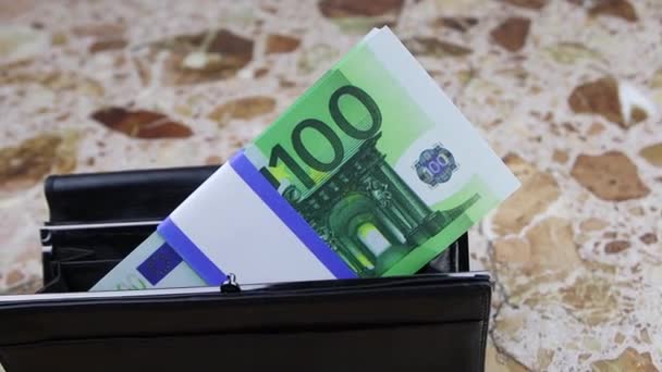 A bundle of 100 euro banknotes lies in a black wallet on a stone table, FullHD — Stock Video