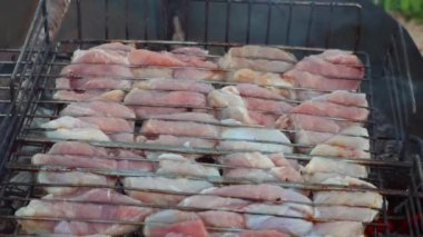 Büyük et parçaları metal tel askıda sıcak kömürlerde yavaşça pişirilir. Tam HD