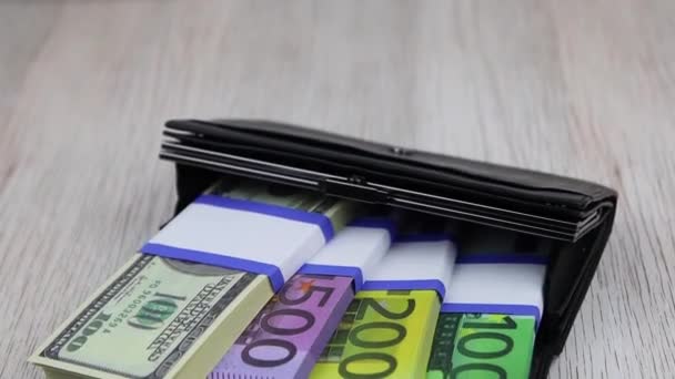 Paquetes de billetes de 100, 200, 500 euros y 100 dólares yacen en una billetera negra — Vídeos de Stock