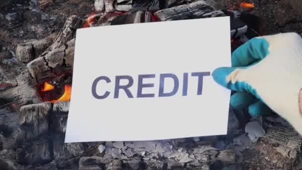 Parola di credito su un foglio bianco di carta brucia in un fuoco contro. — Video Stock