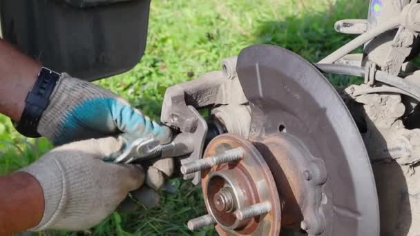 Gloved worker repairing car brakes against green grass background, FullHD — Stock Video