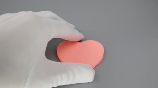Händerna i vita handskar placera rullade 10 eurosedlar på ett hjärtformat klistermärke — Stockvideo