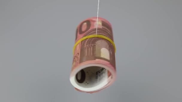 Curled 10 euro banknotes rotate on a thread on a gray background, close-up. — Stock Video