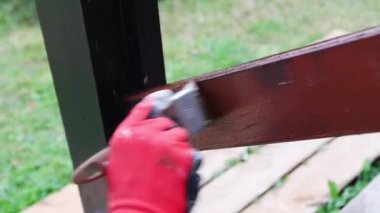 Kırmızı iş eldivenli kadın püsküllü ahşap tırabzanları kahverengi boyuyor.