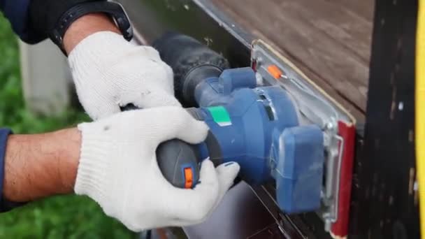 Un lavoratore tratta la superficie laterale dei corrimano in legno con una levigatrice vibrante — Video Stock