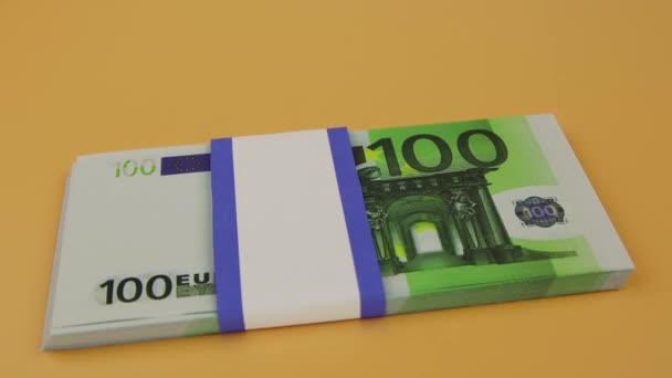 Bundel van 100 euro valt op tafel en de hand legt de opgerolde biljetten bovenop — Stockvideo