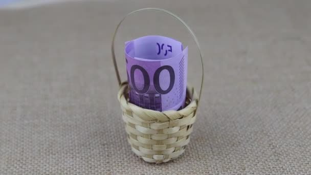 Převinuté 500 eurobankovek uložených v malém koši se otáčejí na kulatém stole — Stock video