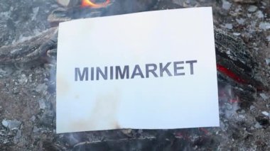 Kelime Minimarket beyaz bir yaprak üzerinde ateş içinde yanıyor. Yavaş çekim
