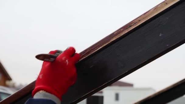 Pracownica w czerwonych rękawiczkach maluje pędzlem boczną drewnianą poręcz brązową. W pełni HD — Wideo stockowe