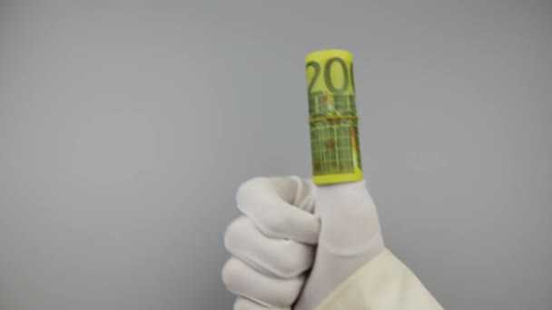 La mano en un guante blanco muestra un pulgar hacia arriba, con unos billetes de 200 euros retorcidos puestos en él — Vídeos de Stock