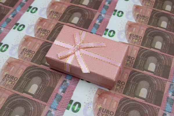 A caixa de presente cor-de-rosa encontra-se em 10 notas de euro alinhadas sucessivamente. Close-up — Fotografia de Stock