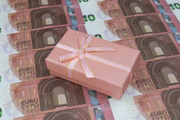 A caixa de presente cor-de-rosa encontra-se em 10 notas de euro alinhadas sucessivamente. Close-up — Fotografia de Stock