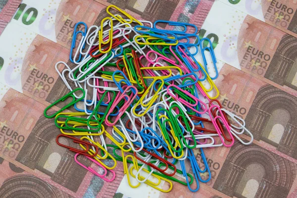 Bir demet renkli ataç 10 Euro banknotun üzerinde yatıyor. Kapat.