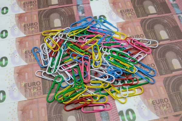 Un groupe de trombones multicolores repose sur 10 billets en euros. Gros plan — Photo