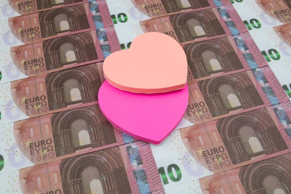 Kalp şeklinde renkli çıkartmalar serilmiş 10 avroluk banknotların üzerinde.