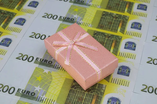 Caixa de presente rosa encontra-se em 200 notas de euro dispostas em uma fileira — Fotografia de Stock