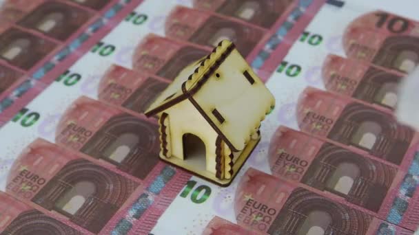 Guante de mano en blanco elimina casa de madera con un montón de billetes de 10 euros — Vídeos de Stock
