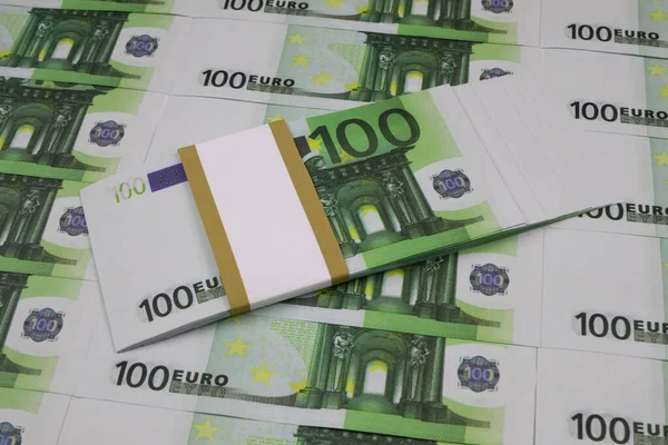 Un paquet de billets en euros se trouve sur un tas de 100 billets en euros disposés en rangée — Photo