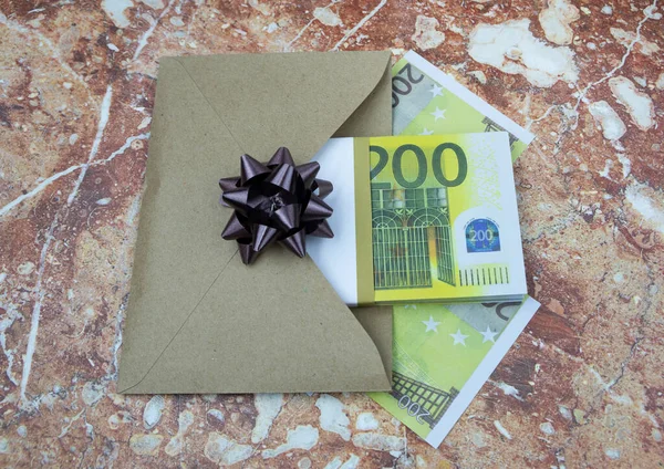 Egy köteg 200 eurós bankjegy egy szürke borítékban fekszik egy kőasztalon. — Stock Fotó