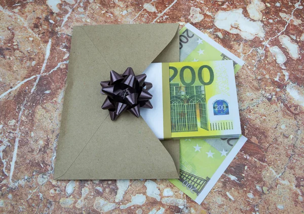 A bundle of 200 euro banknotes lies in a gray envelope on a stone table