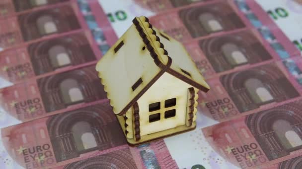 Hand in white glove picks up a small house standing on a pile of 10 euro bills — Stock Video