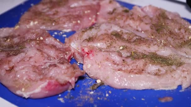 Pechuga de pollo con especias se encuentra en un primer plano tablero azul — Vídeos de Stock