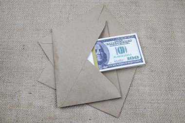 A bundle of 100 dollar bills lies in a brown envelope on a pile of envelopes