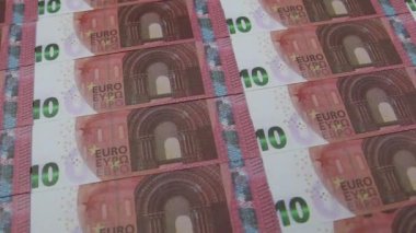 Colored paper clips falling from above on a pile of 10 Euro banknotes